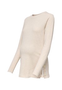 Μπεζ μακρυμάνικη εγκυμοσύνη πουλόβερ με στρογγυλή λαιμόκοψη και λεπτομέρειες με κουμπιά στην αριστερή πλευρά κοντά στη λωρίδα.