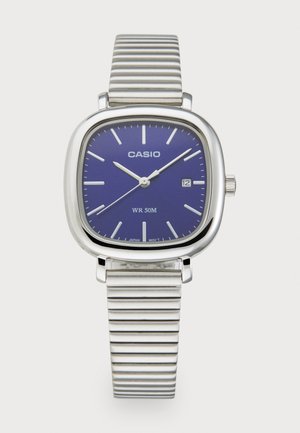 Casio laikrodis su kvadratiniu nerūdijančio plieno korpusu, tamsiai mėlynu ciferblatu, sidabriniais žymekliais ir tekstūruota nerūdijančio plieno apyranke. Atsparus vandeniui iki 50 m.