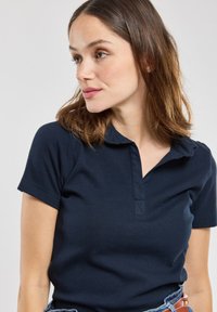 Polo a maniche corte blu navy con colletto, realizzato in un tessuto testurizzato, con una chiusura a bottoni e una vestibilità comoda.
