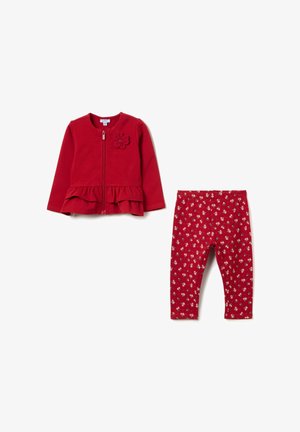 Chaqueta roja con cremallera y dobladillo con volantes, decorada con flores, combinada con leggings rojos que presentan pequeños patrones florales blancos. Material suave y diseño casual.