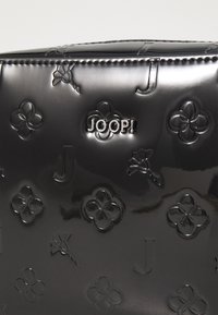 Borsa nera lucida con motivi floreali e letterali in rilievo. Include un logo sollevato "JOOP!" con dettagli in hardware argentato.