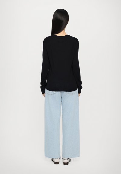 Zwarte lange mouwen top gecombineerd met lichtblauwe wijde jeans. De stof is zacht en glad, met een eenvoudig, casual ontwerp en een recht gesneden silhouet.