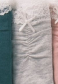 Primo piano di tre tessuti piegati: teal, pizzo grigio chiaro con fiocco e arricciatura, e rosa chiaro con dettagli in pizzo.