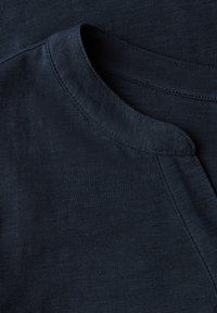 Tissu de T-shirt texturé bleu marine avec un col rond et des détails de couture visibles. Fini lisse avec un léger éclat.