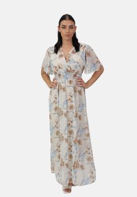Robe longue fleurie en crème avec des motifs de fleurs bleues et brunes, en tissu léger, décolleté en V et taille smockée pour un ajustement décontracté.