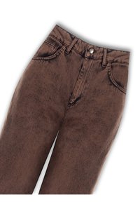 Jean en denim marron avec une texture légèrement délavée, comportant cinq poches et une fermeture à bouton métallique à la taille.