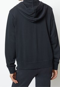 Felpa nera con cappuccio realizzata in un tessuto liscio, dotata di tasca a canguro e polsini a coste, che presenta un design minimalista e un aspetto casual.
