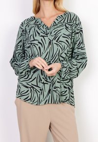 Camicia verde chiaro con motivo astratto nero, design senza colletto, maniche lunghe con polsini elasticizzati e vestibilità rilassata.