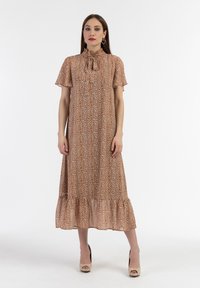 Rochie midi maro cu un model floral, mâneci scurte, tiv volanat și un guler înalt cu detaliu de fundă. Purtați cu tocuri de culoare deschisă.