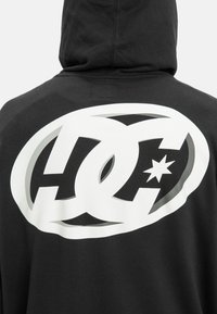 Black hoodie featuring a large white DC logo and star graphic on the back. The fabric appears soft with a relaxed fit.