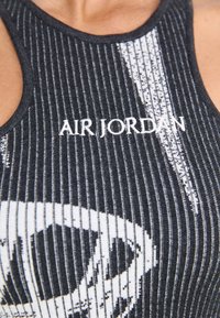 Juodas raštuotas liemenėles su balta grafika ir "AIR JORDAN" tekstu. Su lenkta nugarine dalimi ir tekstūruotu audiniu.