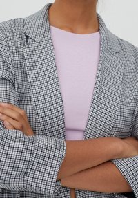 Gray and black checked blazer with notched lapels, paired with a lightweight lavender ribbed top. Fabric appears smooth with structured sleeves.