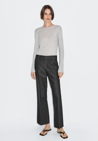 Gray ribbed long-sleeve top paired with high-waisted dark denim trousers featuring a straight leg, minimalist design, and subtle stitching.