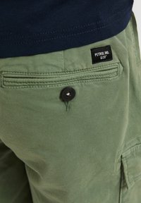 Grüne Baumwoll-Cargoshorts mit einer Gesäßtasche, die einen schwarzen Knopf und ein Label mit der Aufschrift "PETROL IND. & CO." trägt. Strukturierter Stoff, lockere Passform.