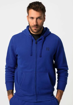 Blue zip-up hoodie made of soft fabric, featuring a black logo on the chest, front pockets, and drawstring hood. Smooth texture.