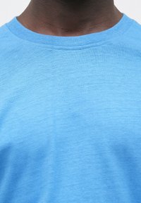 Hele sinine t-särk, millel on ümmargune kaelus, pehme puuvillane materjal ja sile tekstuur, sobib igapäevaseks kandmiseks.