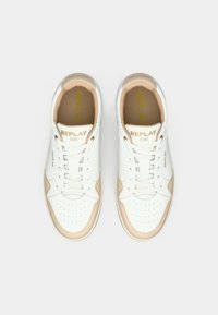 Une paire de baskets blanches avec des accents beige, zone de pointe perforée, lacets blancs, et le logo "REPLAY 1981" sur la languette et sur les côtés.