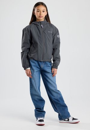 Huppari harmaa vetoketjulla, jossa on elastiset hihansuut ja logopainatus. Yhdistetty löysiin sinisiin farkkuihin ja musta-valkoisiin lenkkareihin.