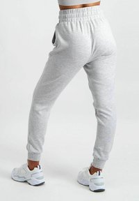 Szare dresy z elastycznym pasem i mankietami, z bocznymi kieszeniami, wykonane z miękkiego materiału. W połączeniu z białymi sneakersami.