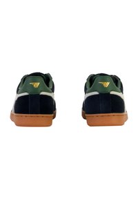 Sneaker in suede blu navy con dettagli verdi, strisce laterali in pelle bianca e suole in gomma marrone. Dettaglio del logo dorato sul tallone.