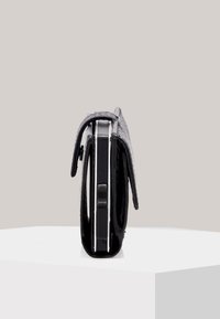 Portafoglio in pelle nera mostrato di lato, con una superficie testurizzata, profilo snello, bordi arrotondati e una chiusura a scatto visibile.