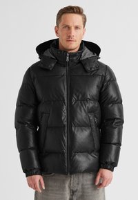 Schwarze Pufferjacke mit glänzender Oberfläche, mit einem Reißverschluss vorne, elastischen Bündchen und einer abnehmbaren grauen Kapuze. Auffälliges gestepptes Design.