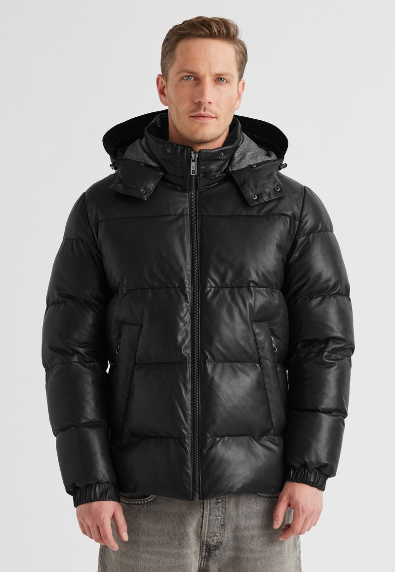 Schwarze Pufferjacke mit glänzender Oberfläche, mit einem Reißverschluss vorne, elastischen Bündchen und einer abnehmbaren grauen Kapuze. Auffälliges gestepptes Design.