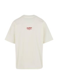 Cremfarbener Baumwoll-T-Shirt, lockere Passform, mit kleinem roten Drucklogo auf dem oberen Rücken. Rundhalsausschnitt und kurze Ärmel.