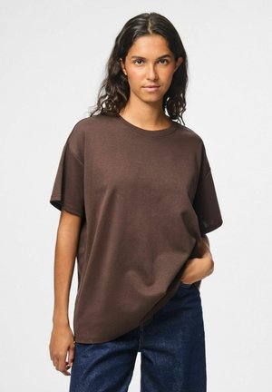 Bruine katoenen t-shirt met een losse pasvorm, korte mouwen en ronde halslijn. Gecombineerd met donkere spijkerbroek. Eenvoudig, effen kleur ontwerp.