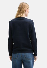 Sudadera azul marino con mangas largas y cuello redondo acanalado. Fabricada con una tela texturizada, cuenta con un dobladillo recto y un ajuste relajado.