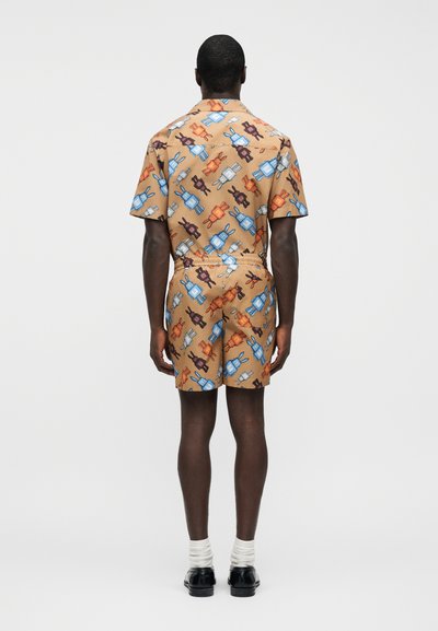 Πουκάμισο με κοντό μανίκι και γιακά και ταιριαστό σορτς από υφασμάτινο σετ με σχέδιο καρτούν με κουνέλια σε μπλε, πορτοκαλί και καφέ πάνω σε ταμπά φόντο.