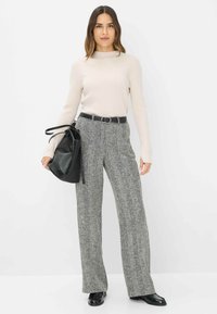 Lichtbeige geribde trui gecombineerd met grijze houndstooth wijde broek. Accessoires zijn een zwarte riem en een zwarte tas.
