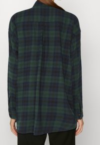 Kariertes Hemd in Dunkelgrün und Marineblau, mit einem Rückenfalt, langen Ärmeln und geknöpften Manschetten. Weicher Stoff und lässige Passform.