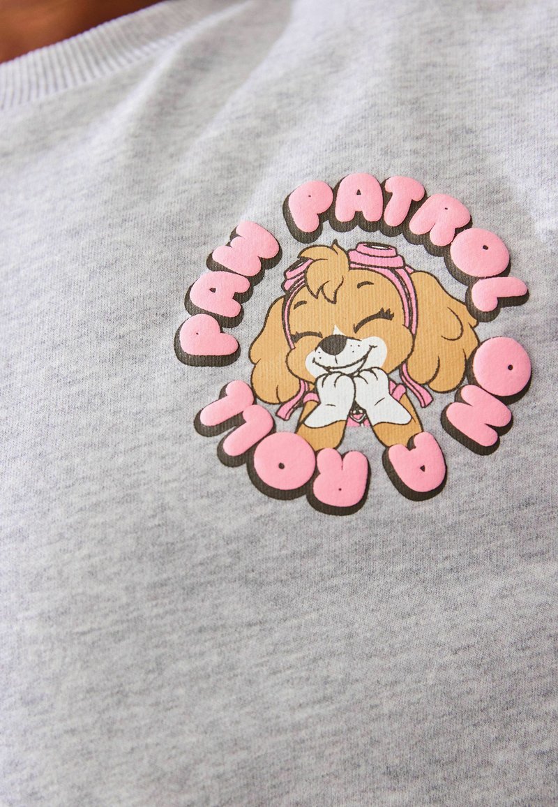Szary bawełniany sweatshirt z kolorową grafiką Skye z Paw Patrol, z różowymi akcentami i zabawnym letteringiem otaczającym wzór.