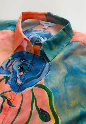 Krāsaina zīda krekls ar ziedu rakstu, kurā redzama zilā roze, oranžs apkaklis un zaļas akcenti. Viegls tekstūra un pogas koraļļu krāsā.