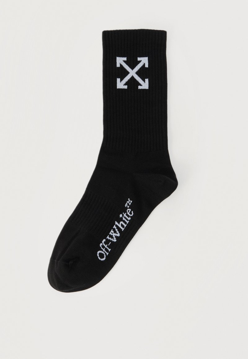 Chaussette unie noire avec logo Off-White™ blanc sur le pied et graphique d'arrows blanches entrecroisées près du haut.