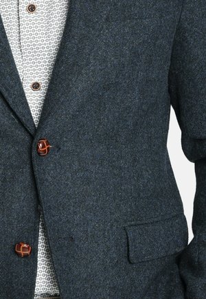 Blazer azul oscuro de espiga, hecho de lana texturizada, con solapa con muesca, bolsillo en el pecho y detalles en botones marrones.