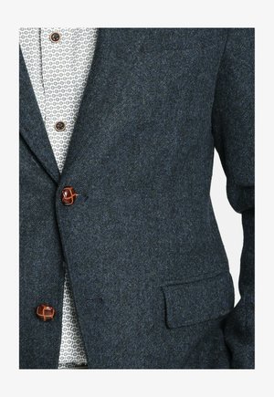 Blazer azul oscuro de espiga, hecho de lana texturizada, con solapa con muesca, bolsillo en el pecho y detalles en botones marrones.