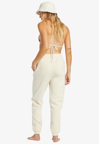 Pantalones jogger de color crema con un ajuste relajado, cinturilla elástica y puños ajustados, combinados con un sombrero tipo cubo a juego.