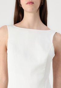 Rochie albă fără mâneci, cu decolteu de tip bateau. Material neted, design ajustat și detalii subtile pe cusăturile laterale. Estetică curată, minimalistă.
