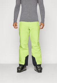 Pantalons de ski vert lime vif avec des accents noirs, présentant un design droit et un matériau imperméable, adaptés aux activités d'hiver.