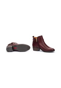 Botas de tobillo de cuero burdeos con un tacón bajo apilado, cierre de cremallera lateral y textura suave. Presenta acentos cosidos y una suela texturizada.