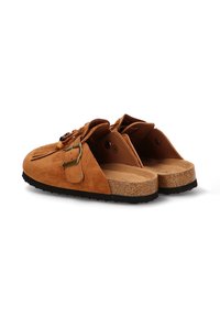 Zapatos de ante color tostado sin cordones con suela de corcho, que cuentan con un detalle de hebilla y un diseño texturizado en la parte superior. Parte trasera abierta sin cobertura del talón.
