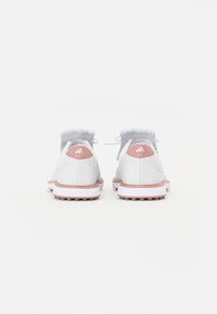 Λευκά και ροζ αθλητικά παπούτσια με υφή στην επάνω πλευρά, στρογγυλή μύτη και καουτσούκ σόλα που διαθέτει μικρές προεξοχές για καλύτερη πρόσφυση.