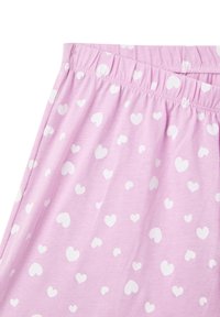 Pantaloni da pigiama corti di colore rosa chiaro con vita elasticizzata, caratterizzati da un motivo di cuori bianchi sparsi di varie dimensioni. Texture morbida.