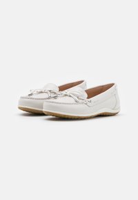Mocasines de cuero blanco con punta redonda, cordones decorativos y acentos de costura. Suela de goma con un patrón de tracción.