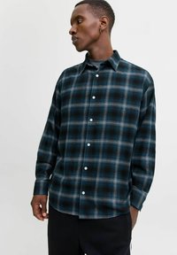 Ruthændet flannel skjorte med blå, sort og grå nuancer; lange ærmer; knaplukning foran; klassisk krave; blød tekstur; afslappet pasform.