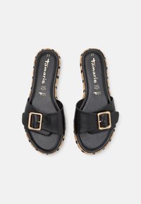 Sandales en cuir noir avec une large sangle et une boucle dorée. Semelle texturée en liège avec des détails tressés et des accents noirs contrastants. Taille 37.