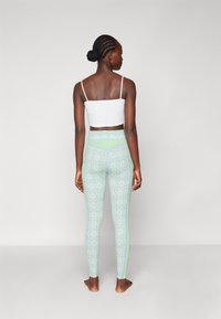 Mint green patterned leggings feature a high waist, smooth texture, and contrasting light blue side accents. White fitted crop top.