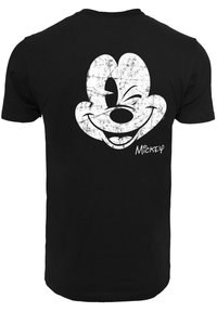 Juodas medvilninis marškinėliai su dideliu, nusidėvėjusiu baltu piešiniu, vaizduojančiu šypsantįsi animacinį pelėdą nugaroje, kartu su "Mickey" tekstu ranka rašyto stiliaus.